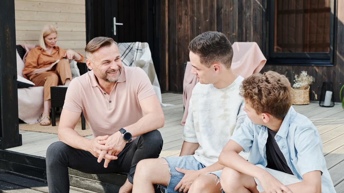 Family sharing quality time on a wooden terrace. Smiling and conversing.